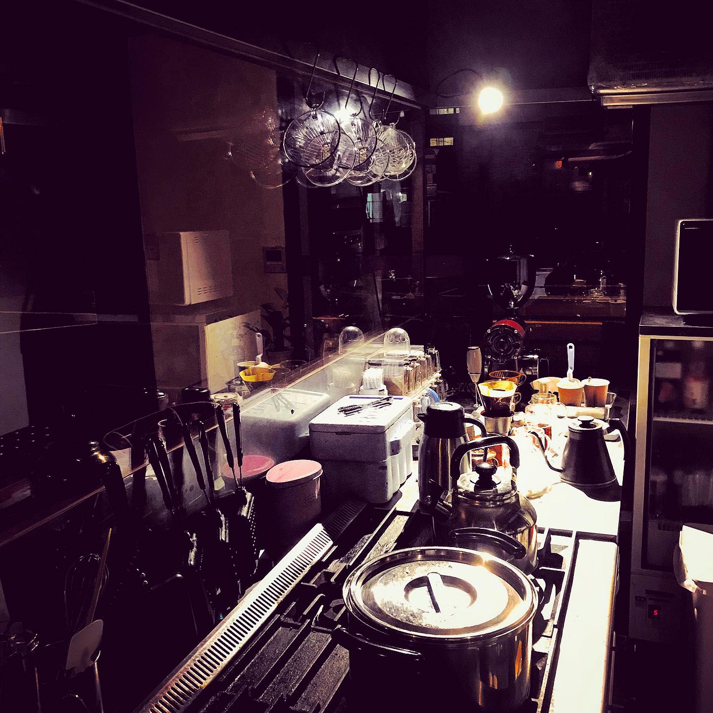 夜に撮影したカウンター内の様子。鍋ややかん、ポット、包丁、コーヒードリッパーなどが並んでいます。